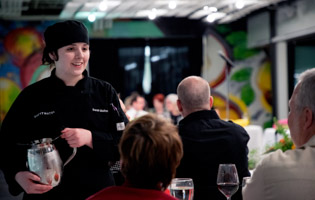 Female culinary student speaking with guests at an event