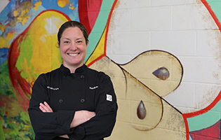 Woman smiling wearing black chef coat